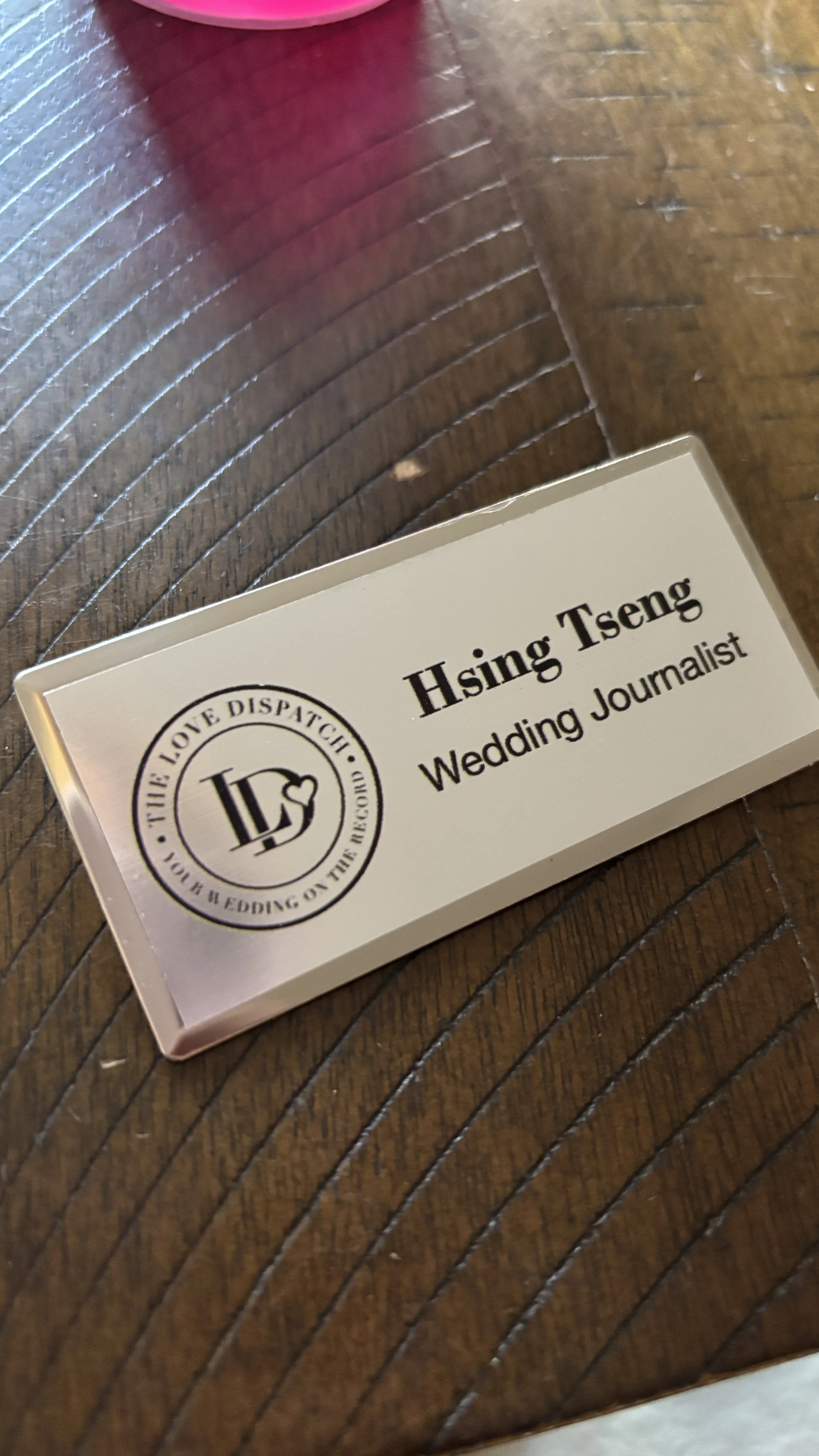 Name tag for Hsing Tseng, a wedding journalist, on a wooden table.