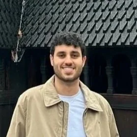Founder of Kallio standing outdoors, smiling, wearing a beige jacket and white shirt