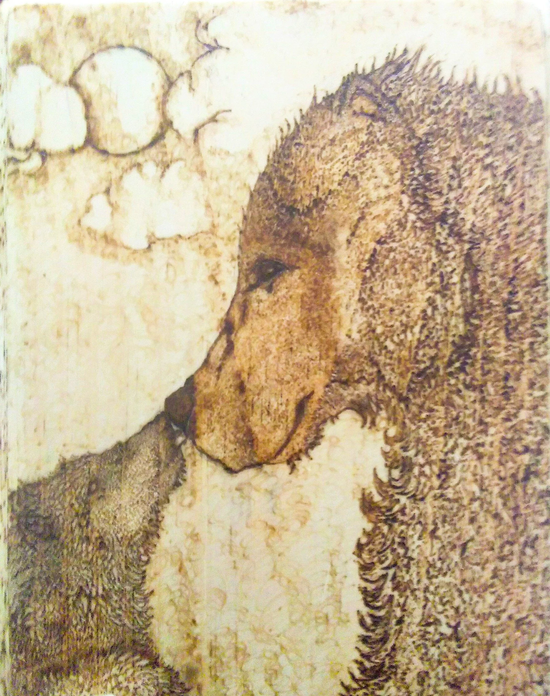A wood burning of a bear and her cub touching noses with what appears to be a moon or sun in the background