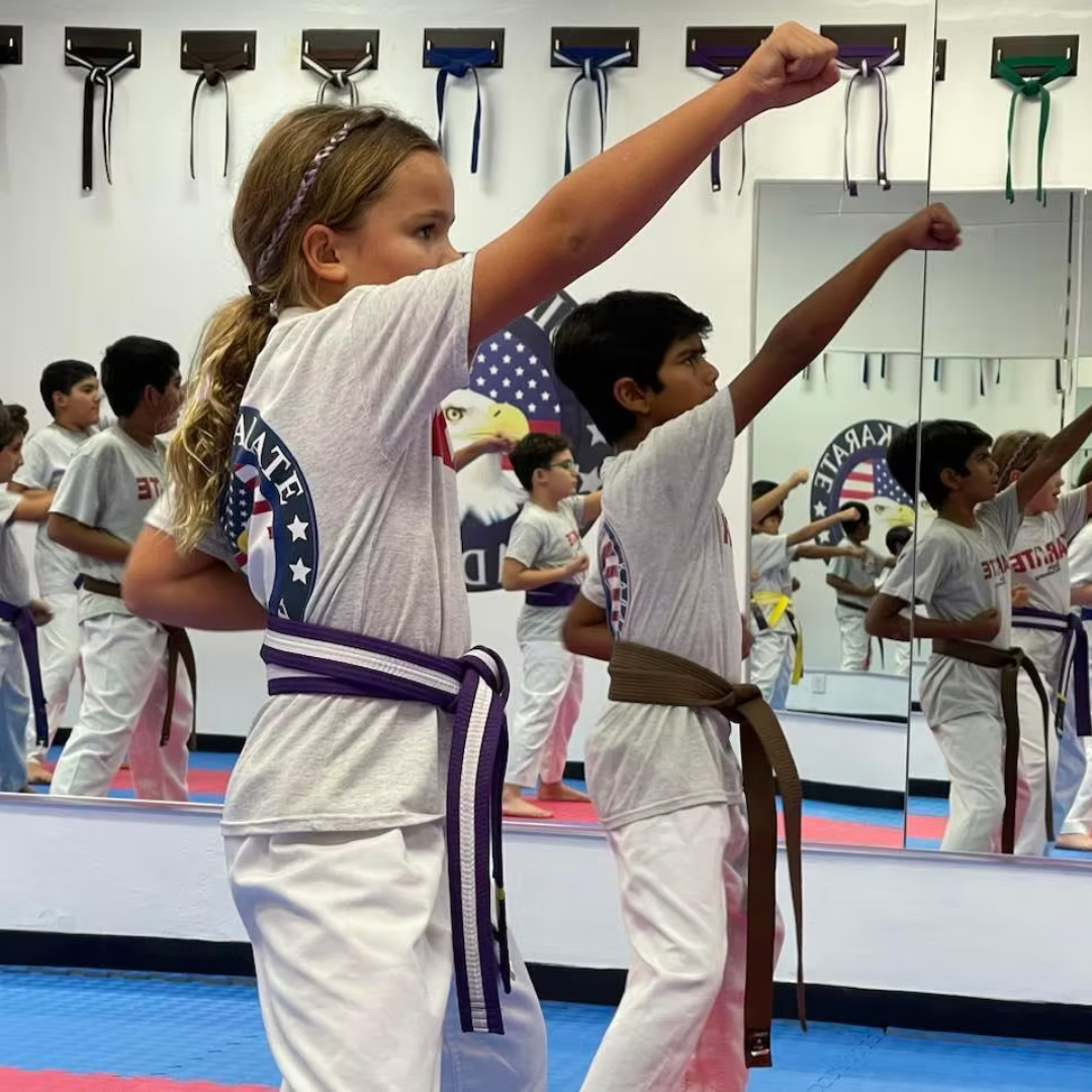 Children practicing martial arts in a dojo, wearing karate uniforms and colored belts.