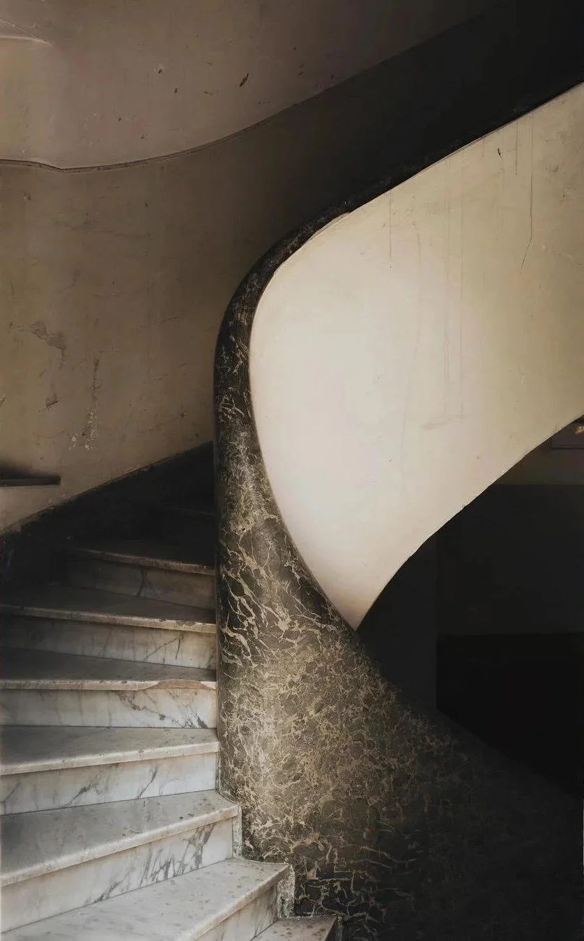 A marble staircase with a black and beige marble handrail in an old building.