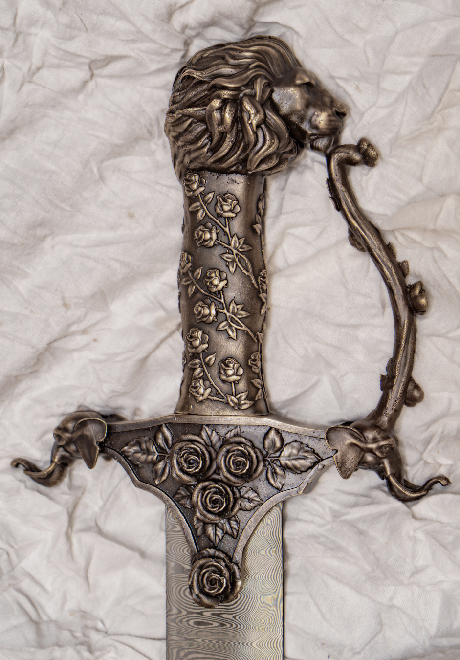 Decorative knife with a lion's head on the handle and floral patterns on the guard and handle.