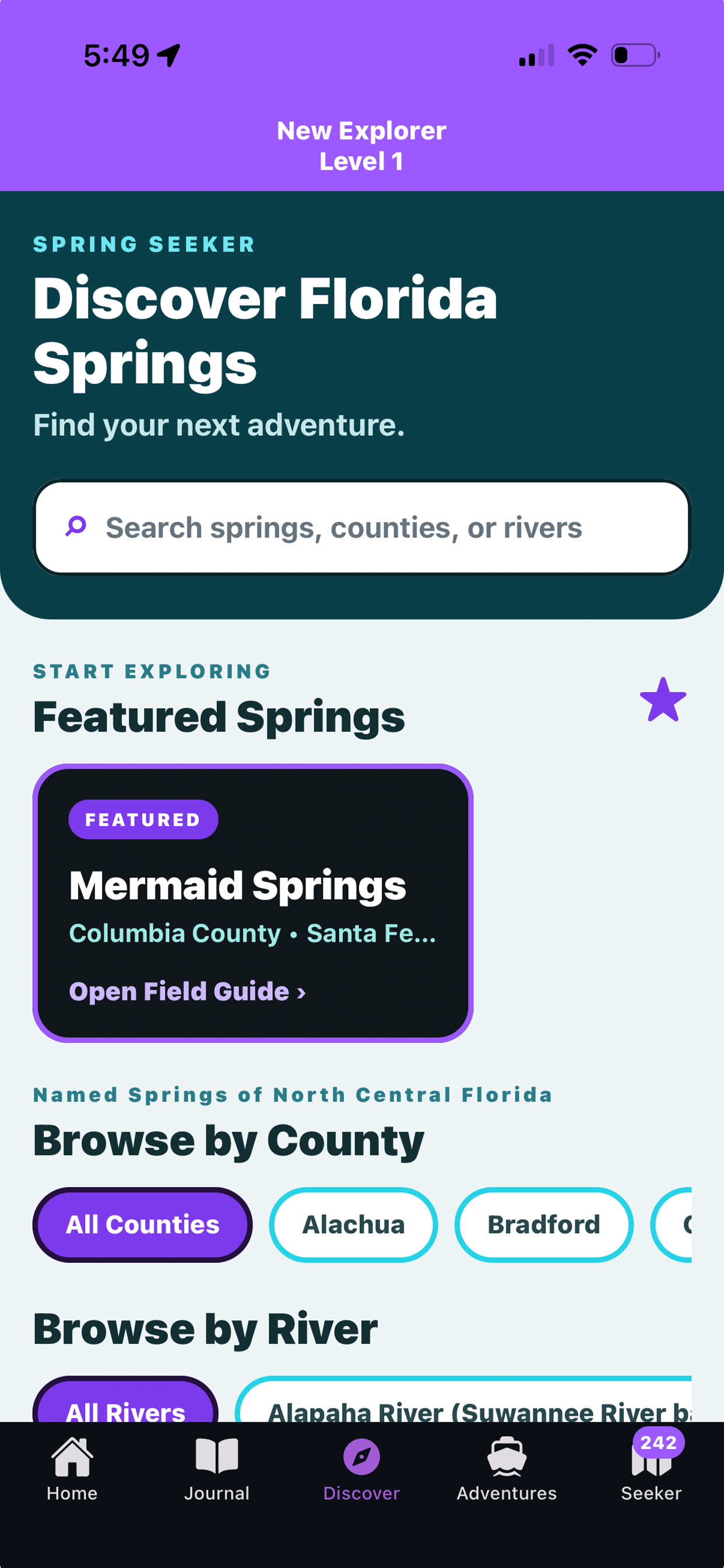 Mobile app screen showing a guide to exploring springs in Florida, featuring a search bar for springs, counties, or rivers, and a list of featured springs including Mermaid Springs in Columbia County. The app has navigation tabs at the bottom labeled Home, Journal, Discover, Adventures, and Seeker.
