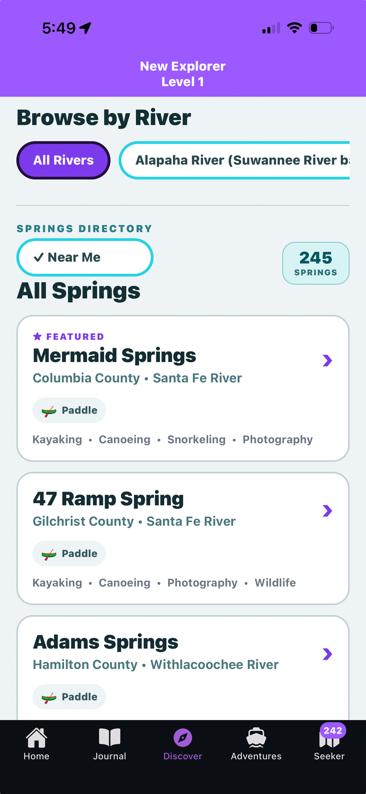 Screenshot of a mobile app interface for exploring rivers and springs, displaying options for browsing by river such as Alapha River, and listing springs like Mermaid Springs, 47 Ramp Spring, and Adams Springs, with navigation menu icons at the bottom.