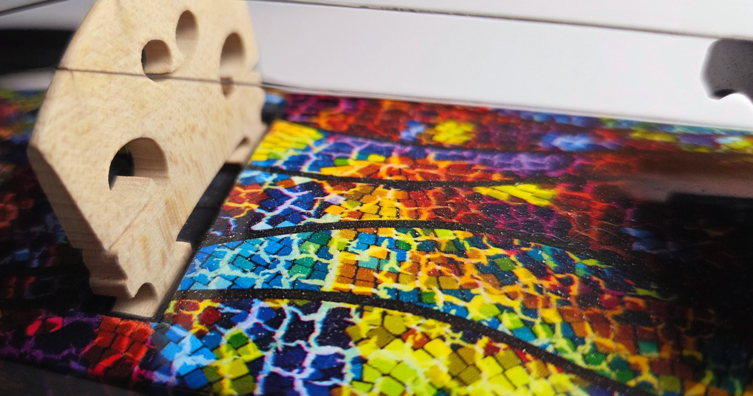 Close-up of a colourful electric violin between the bridge and the fingerboard.