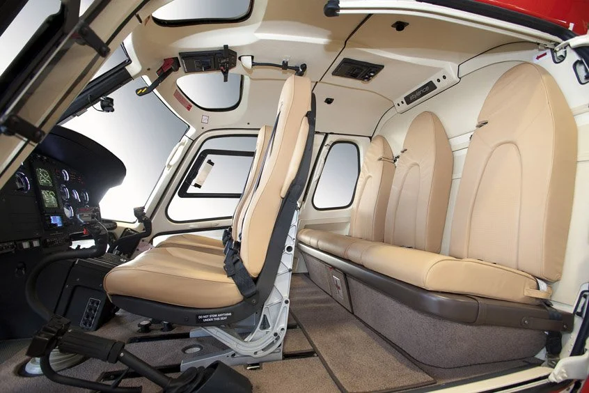 Interior of a Airbus AS350 Helicopter with beige leather seating and cockpit with control panels.
