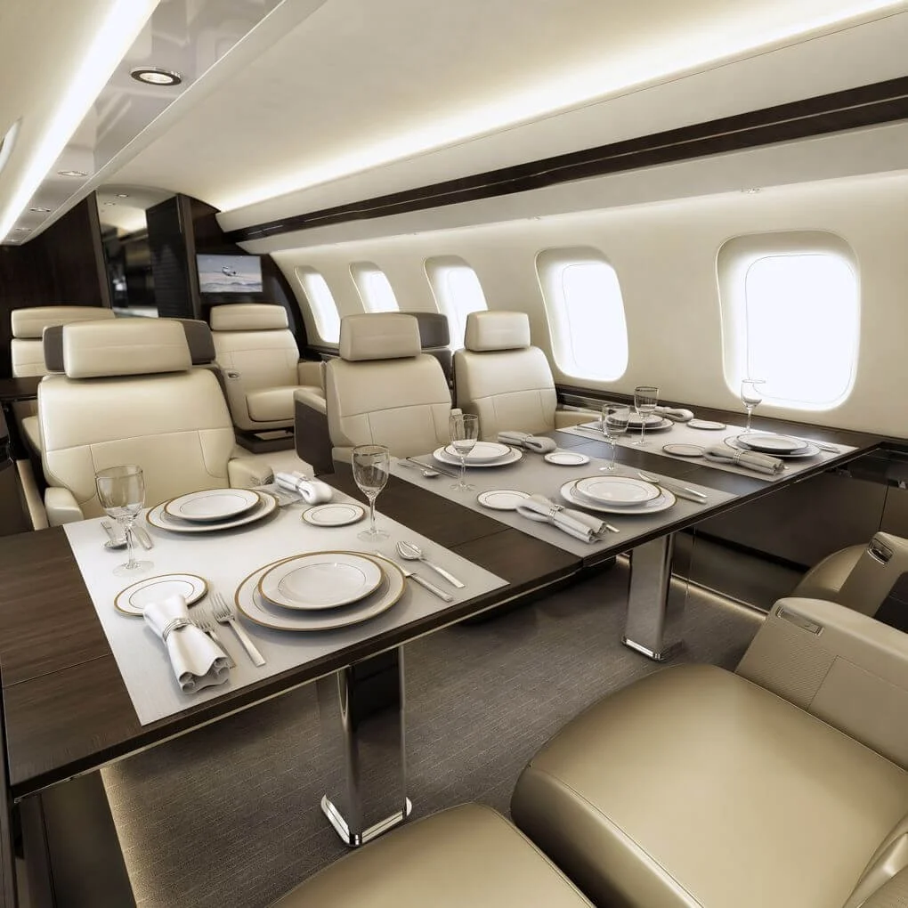 Bombardier Global 7500 – Ultra Long-Range Luxury Private Jet interior with cream leather seating and a dining table set with fine china and glassware.