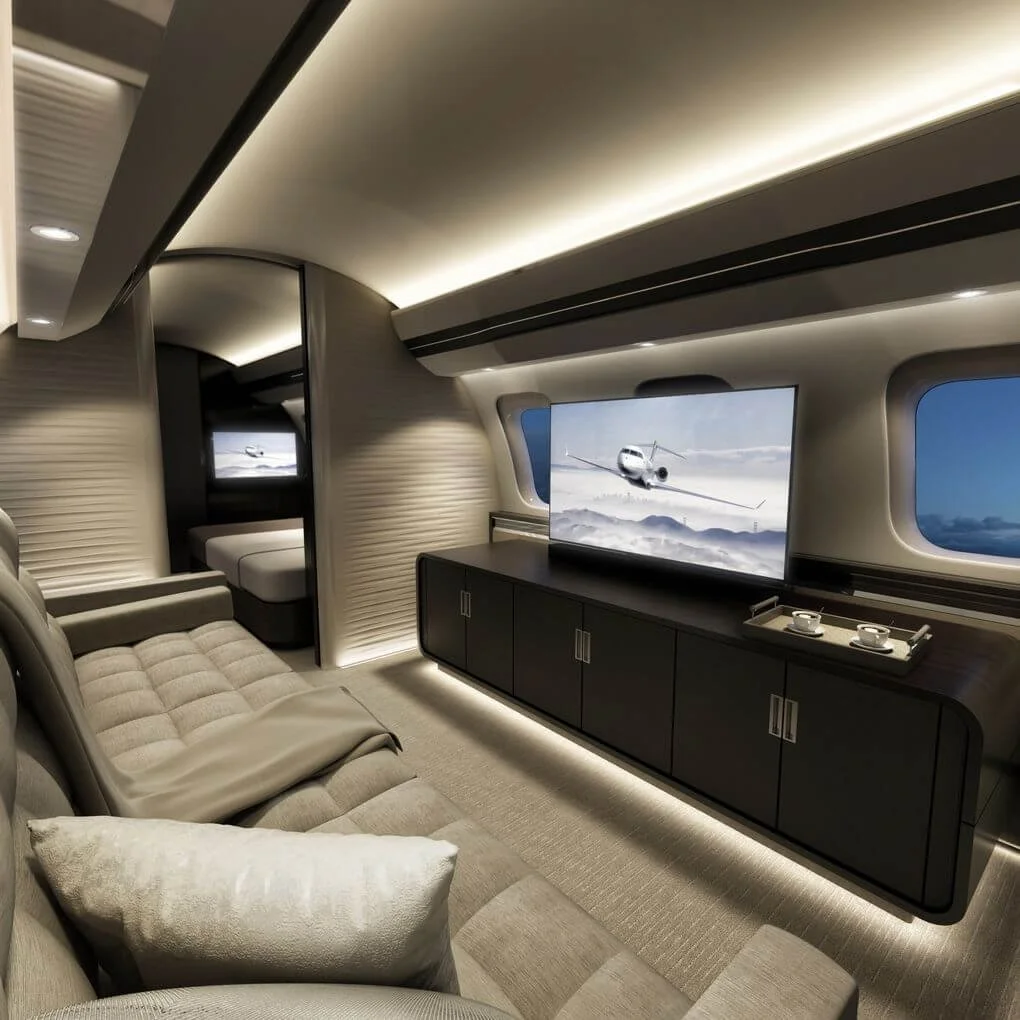 Luxurious private jet interior with plush seating, a large flat-screen TV, sleek cabinetry, and ambient lighting. View of a bed in a partitioned space in the background.