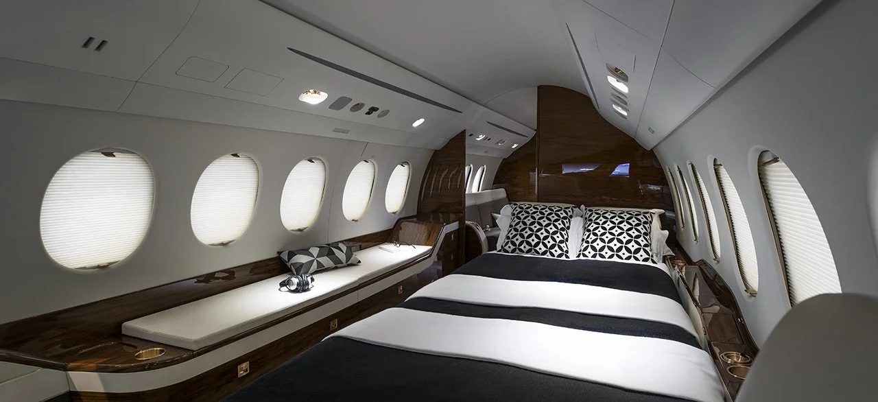 Interior of a private jet with a spacious bed, pillows, and sleek design elements.