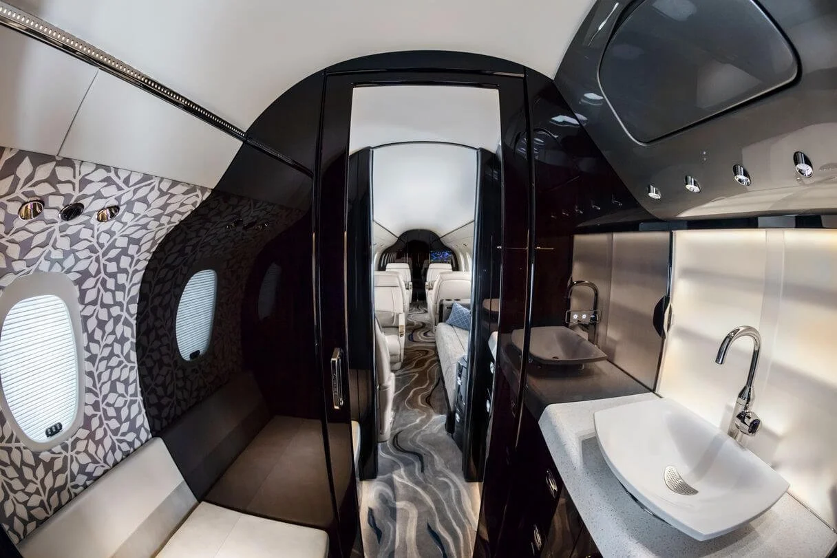 Cessna Citation Longitude Charter interior with modern seating, patterned walls, a small sink, and ambient lighting.