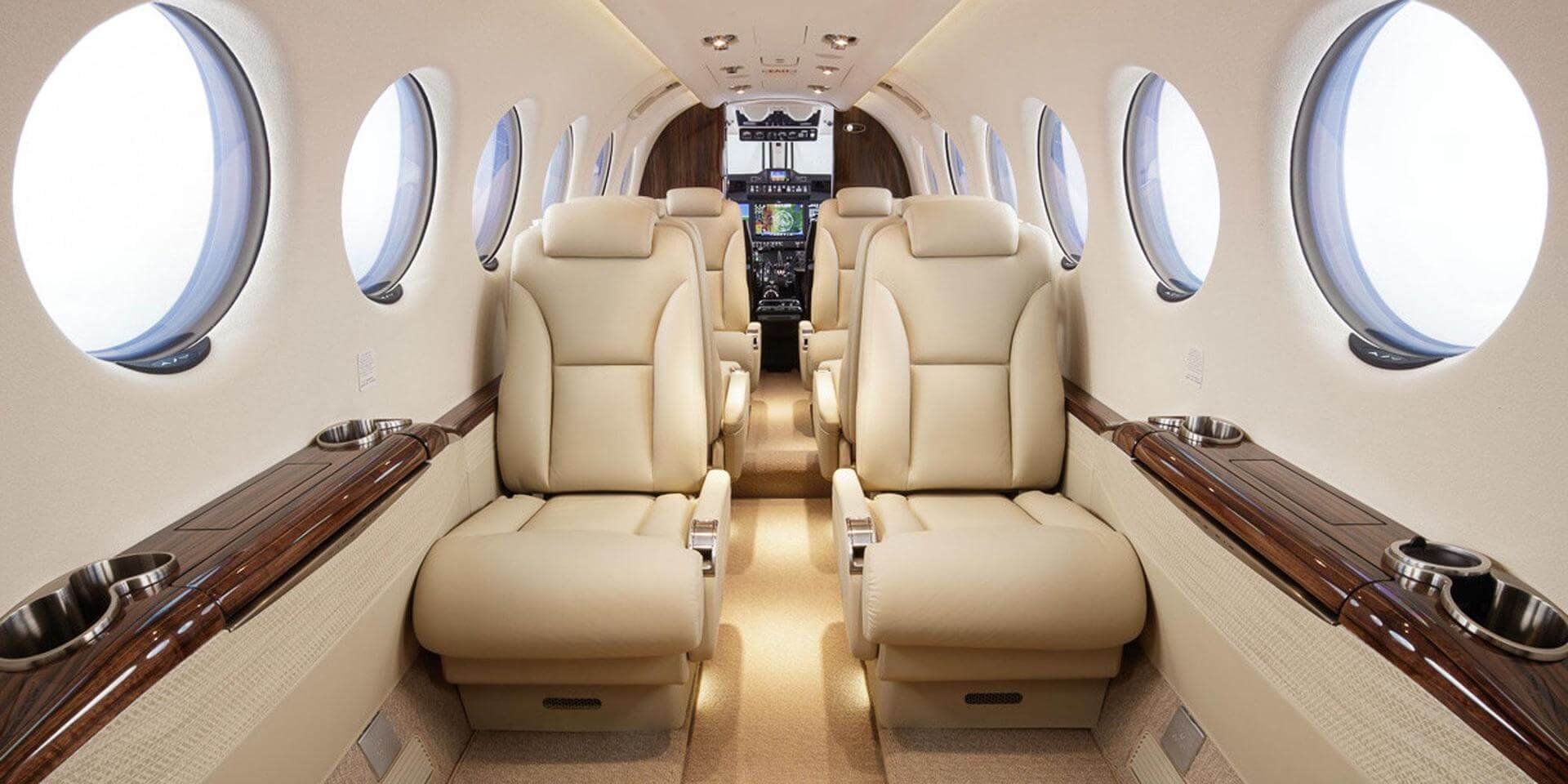 Interior of Beechcraft King Air 350 a private jet with beige leather seats and circular windows.