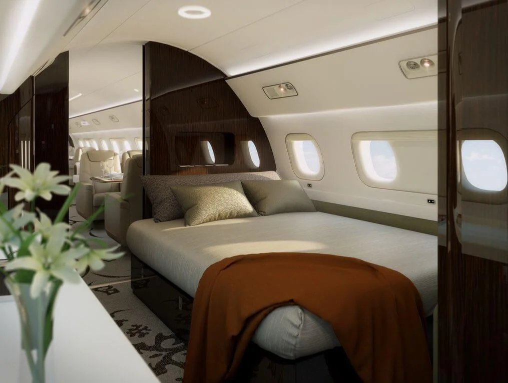 Luxurious private jet interior with a bed and seating area, featuring elegant decor and window views.