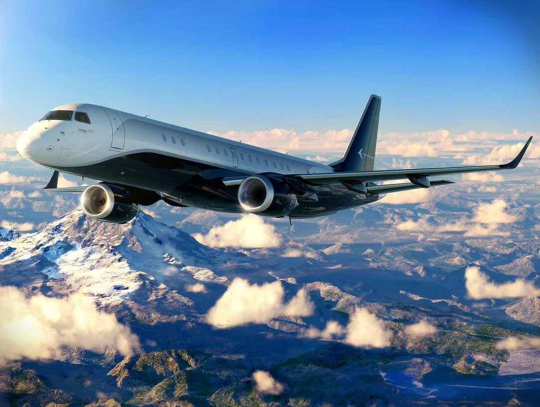 Airplane flying over snow-capped mountains and clouds with blue sky.