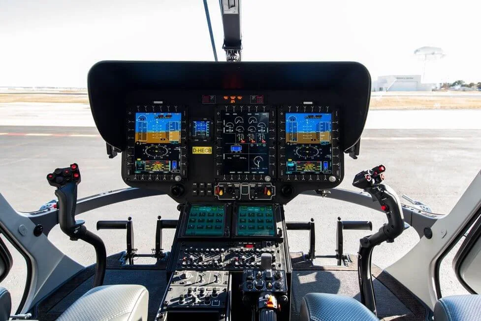 Cockpit of a helicopter with multiple digital screens and controls