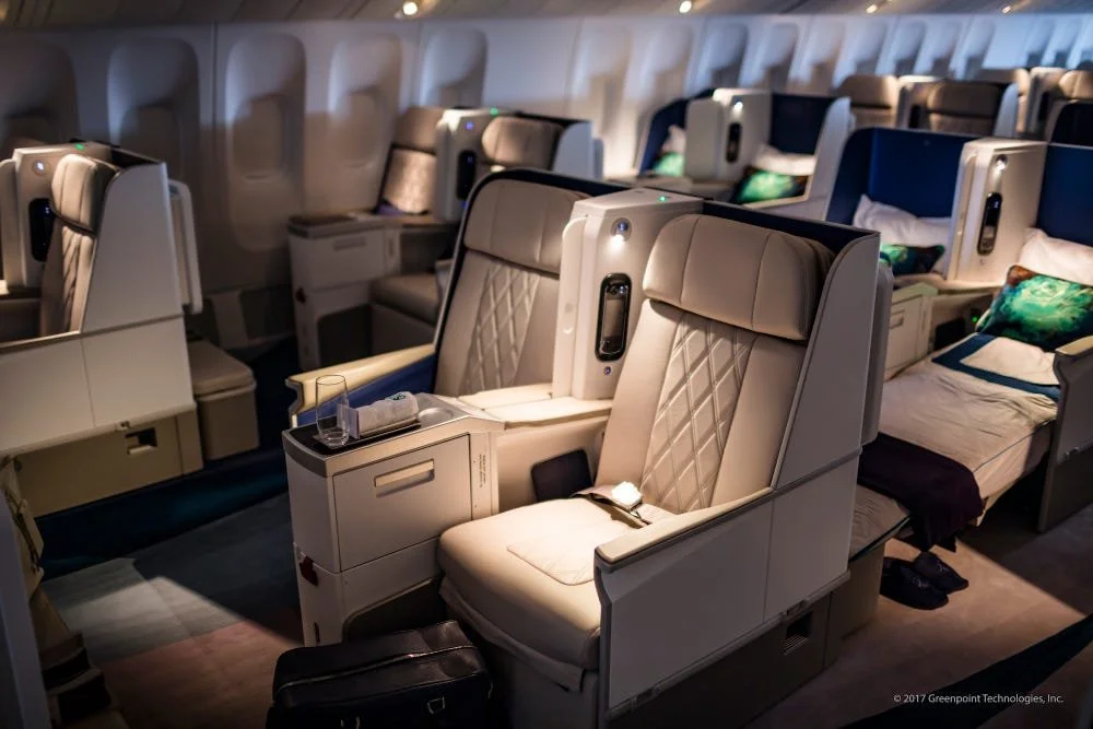 Luxurious airplane business class cabin with comfortable seating and personal amenities.