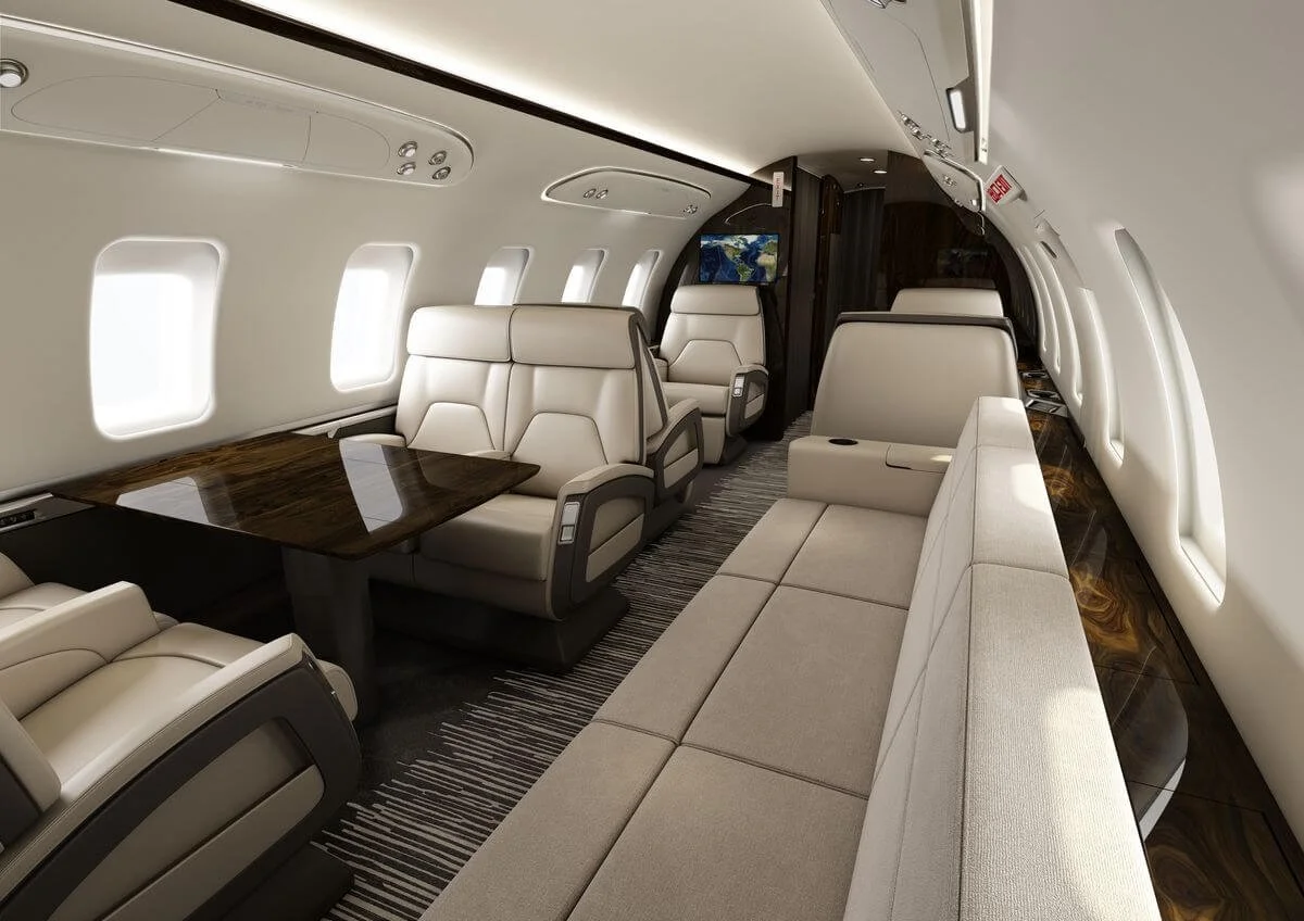 Bombardier Challenger 650 interior with leather seats, a sofa, and a wooden table.