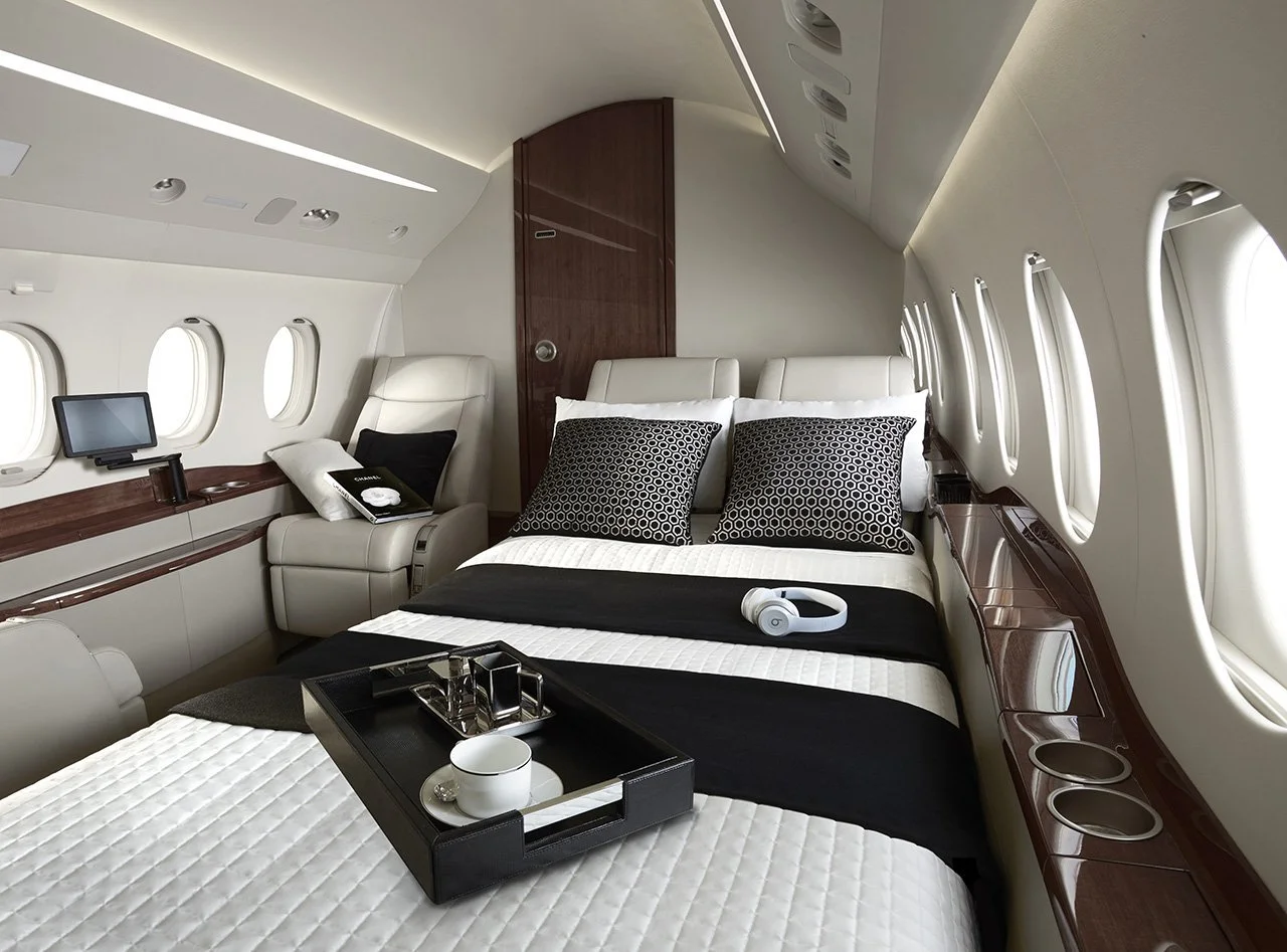 Luxurious private jet interior with a bed, pillows, and tray with a cup, in a sleek modern design.