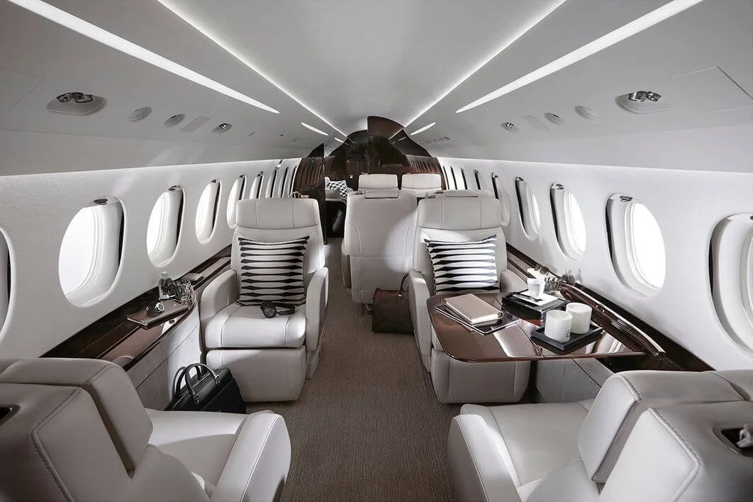 Dassault Falcon 8X Private Jet Charter Luxury private jet interior with leather seats and wooden accents.