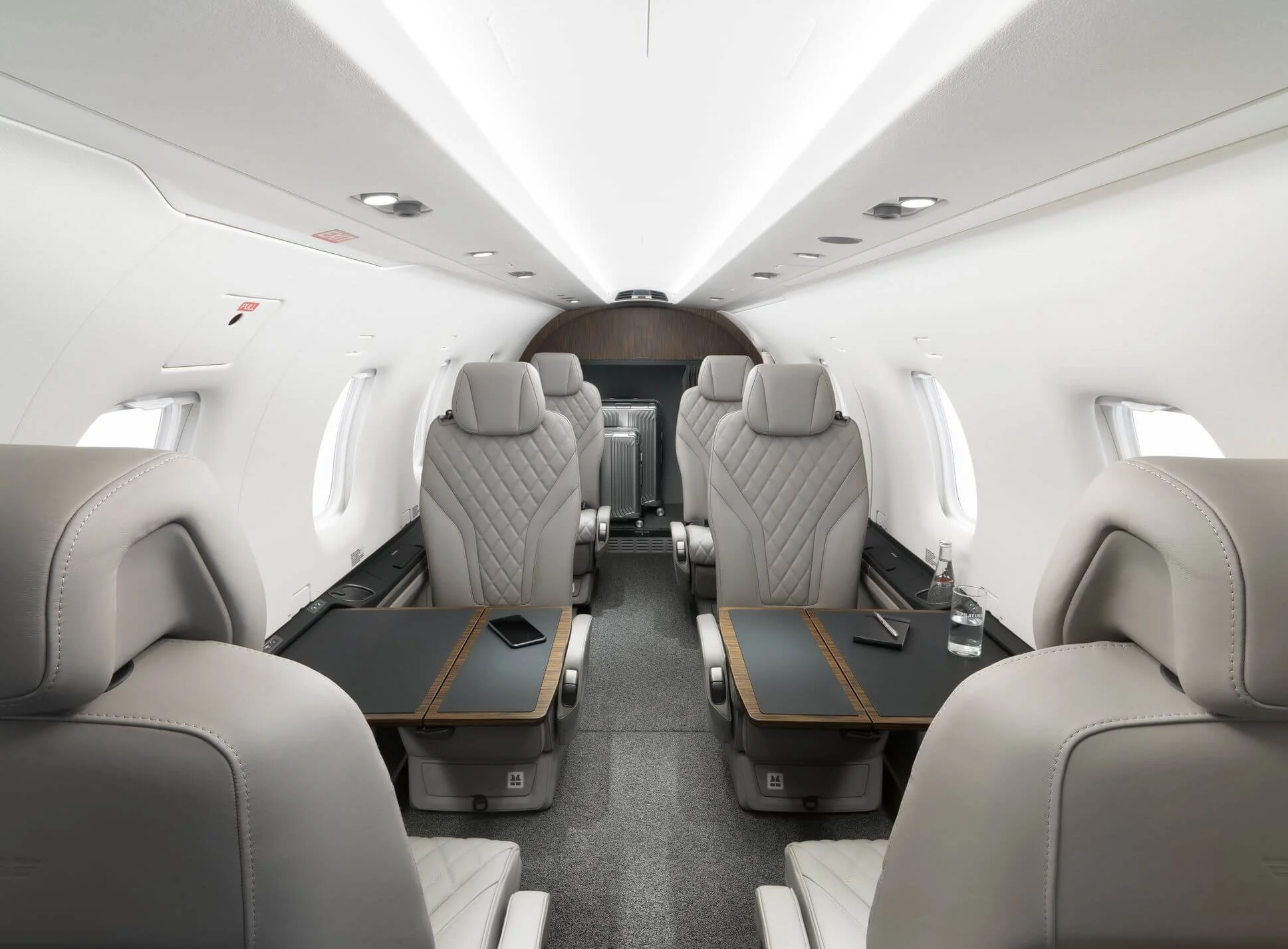 Interior of a luxurious private jet with beige leather seating, fold-out tables, and modern amenities.