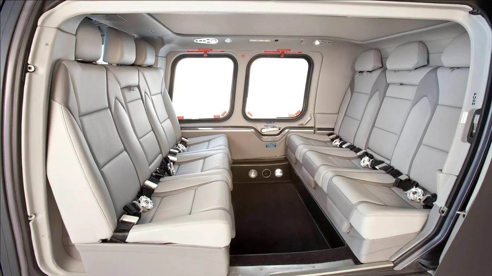 Interior of Agusta A109 Helicopter
 with gray leather seats and seatbelts, arranged in two rows facing each other, and large windows.