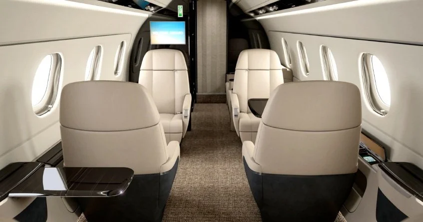 Embraer Legacy 450 interior with beige leather seats and modern design elements.