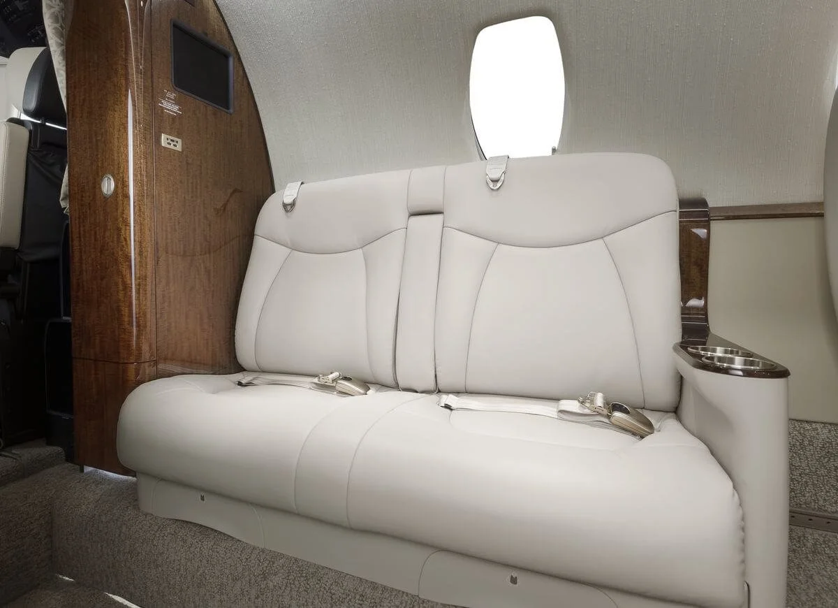 Interior of Cessna Citation XLS Charter  featuring a beige leather seat with seat belts and wood paneling.