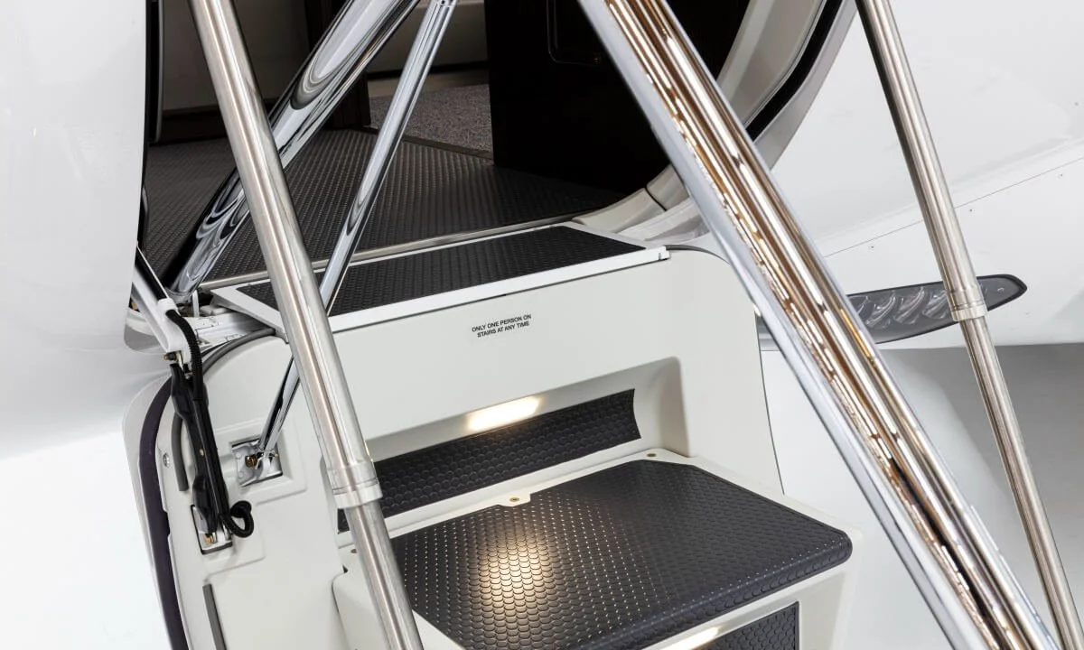 Close-up view of the entry stairs of a private jet, featuring metal railings and textured steps.