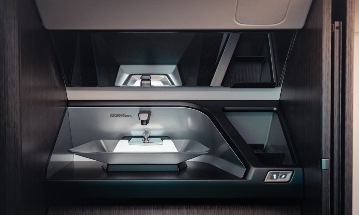 Modern airplane lavatory sink with touchscreen controls and sleek design.