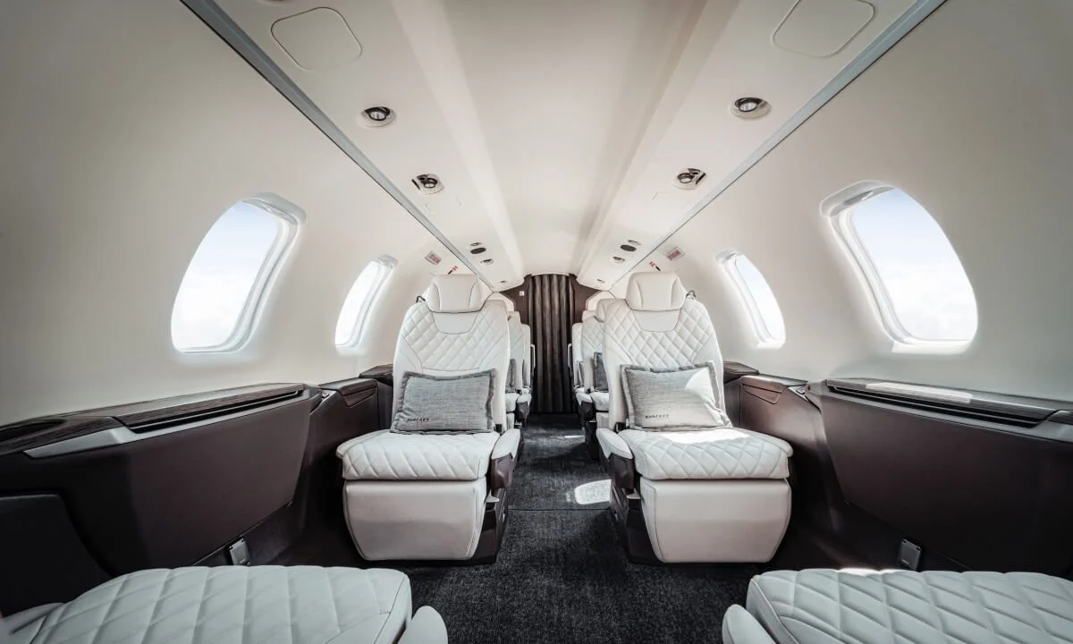 Pilatus PC24 Private Jet Charter interior with cream leather seats and large windows.
