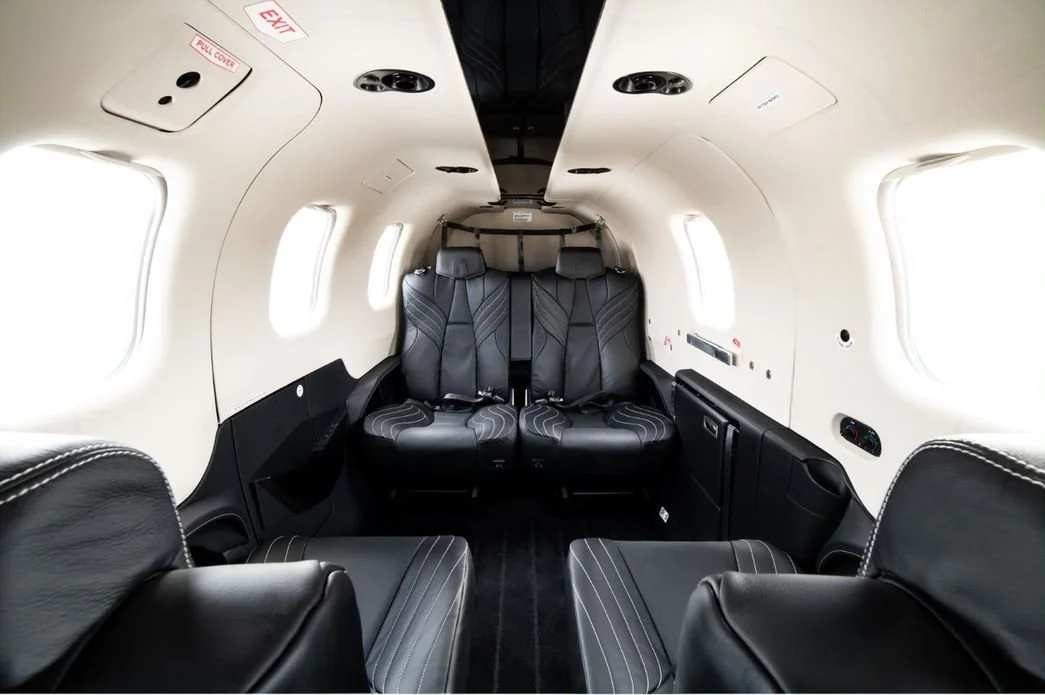 interior of a private jet Daher TBM 940 with black leather seats and white paneling