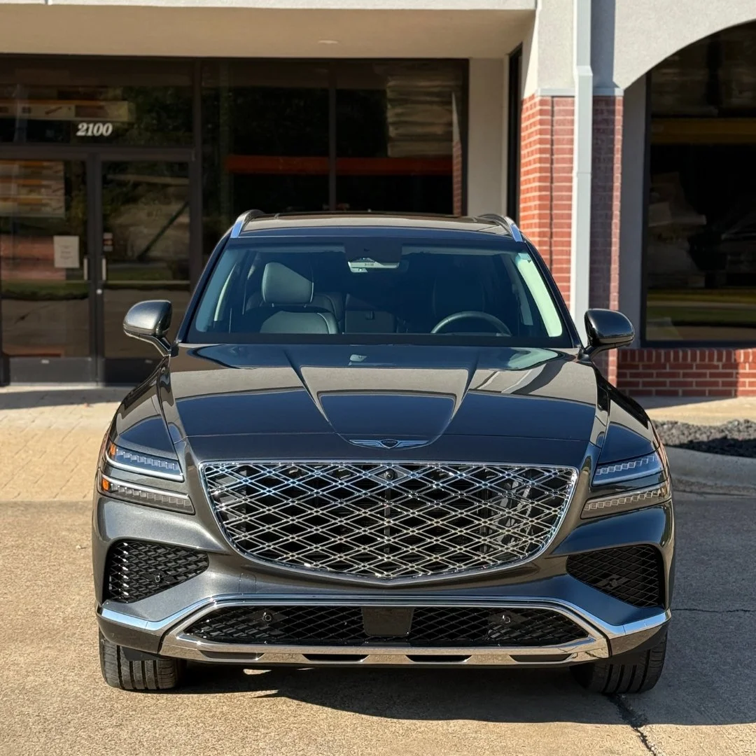 Front view of a black luxury SUV parked outside a building with glass doors and red brick accents.