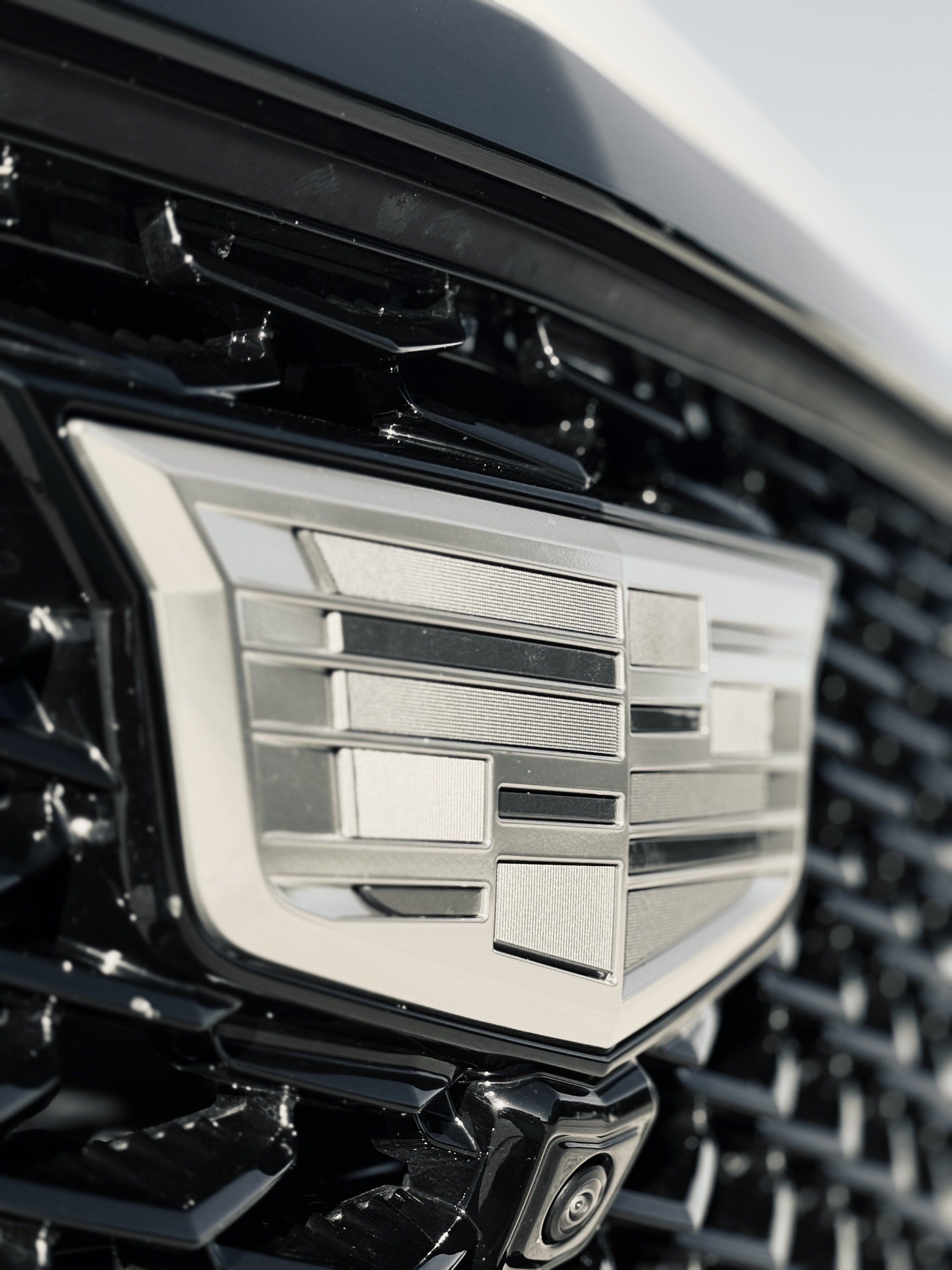 Close-up of a Cadillac emblem on the front of a black vehicle.