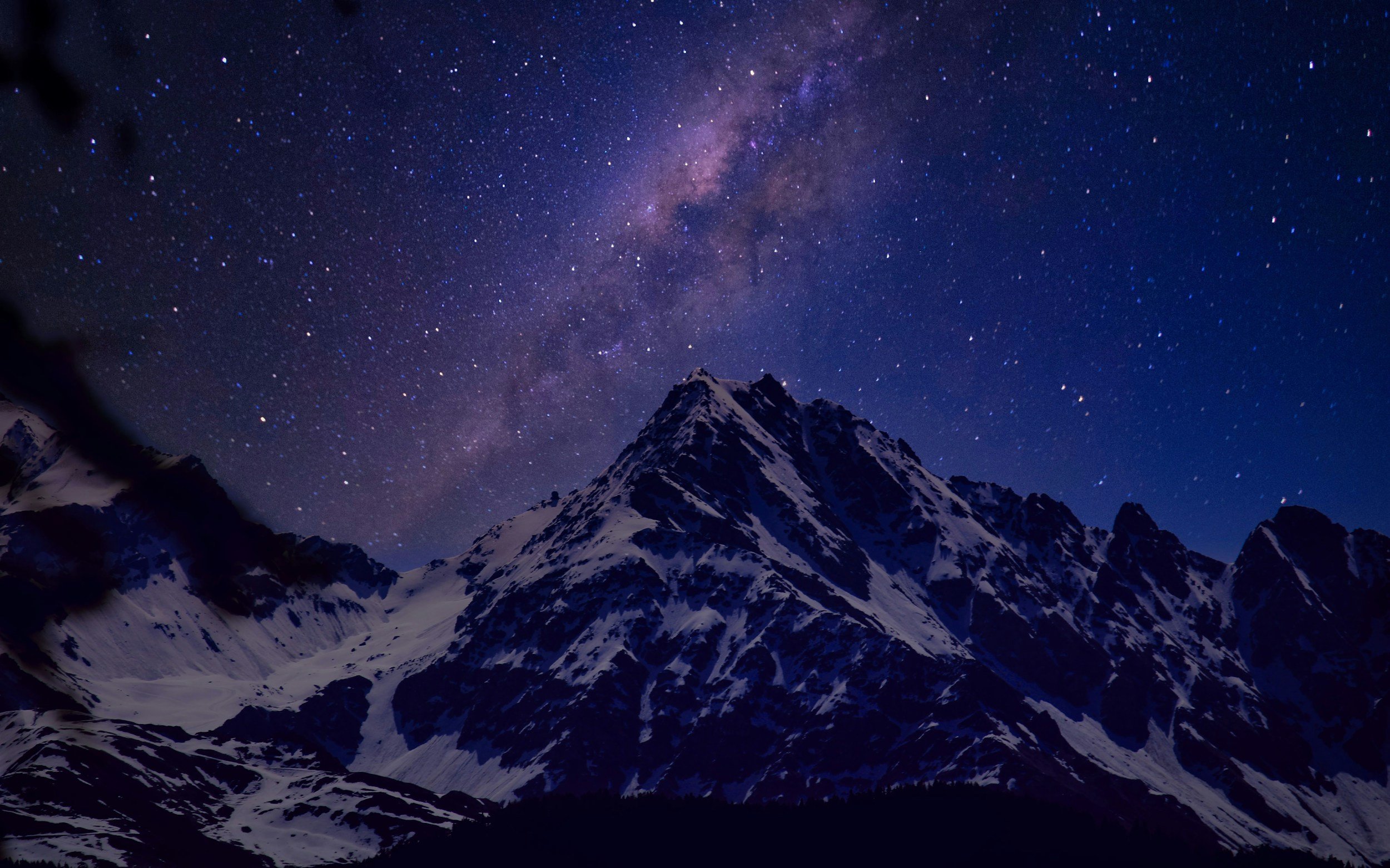 The Milky Way rising over a snow-covered mountain peak on a clear night