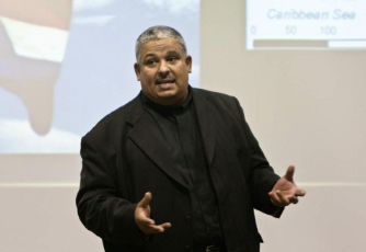 Man giving a presentation in front of a projected map.