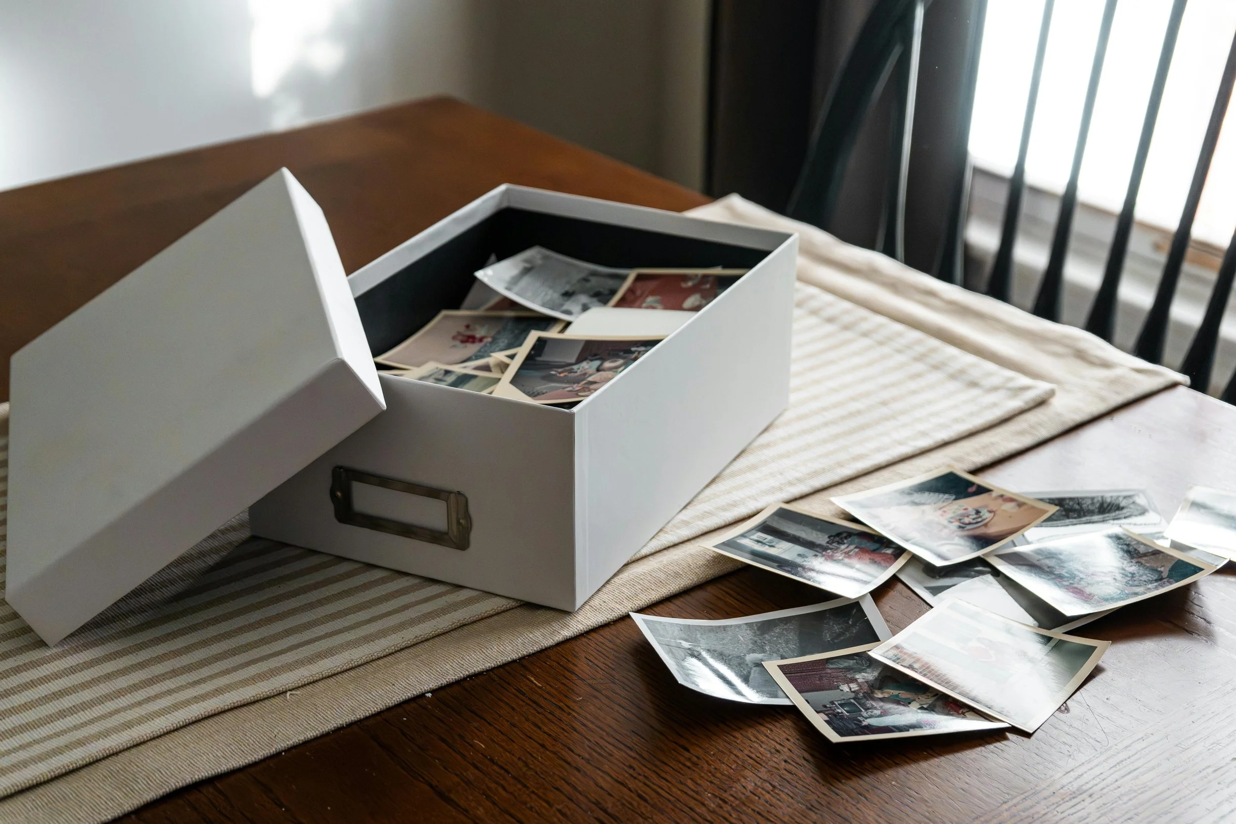 Photo box on dining room table with photos in box and on table ready to be organized