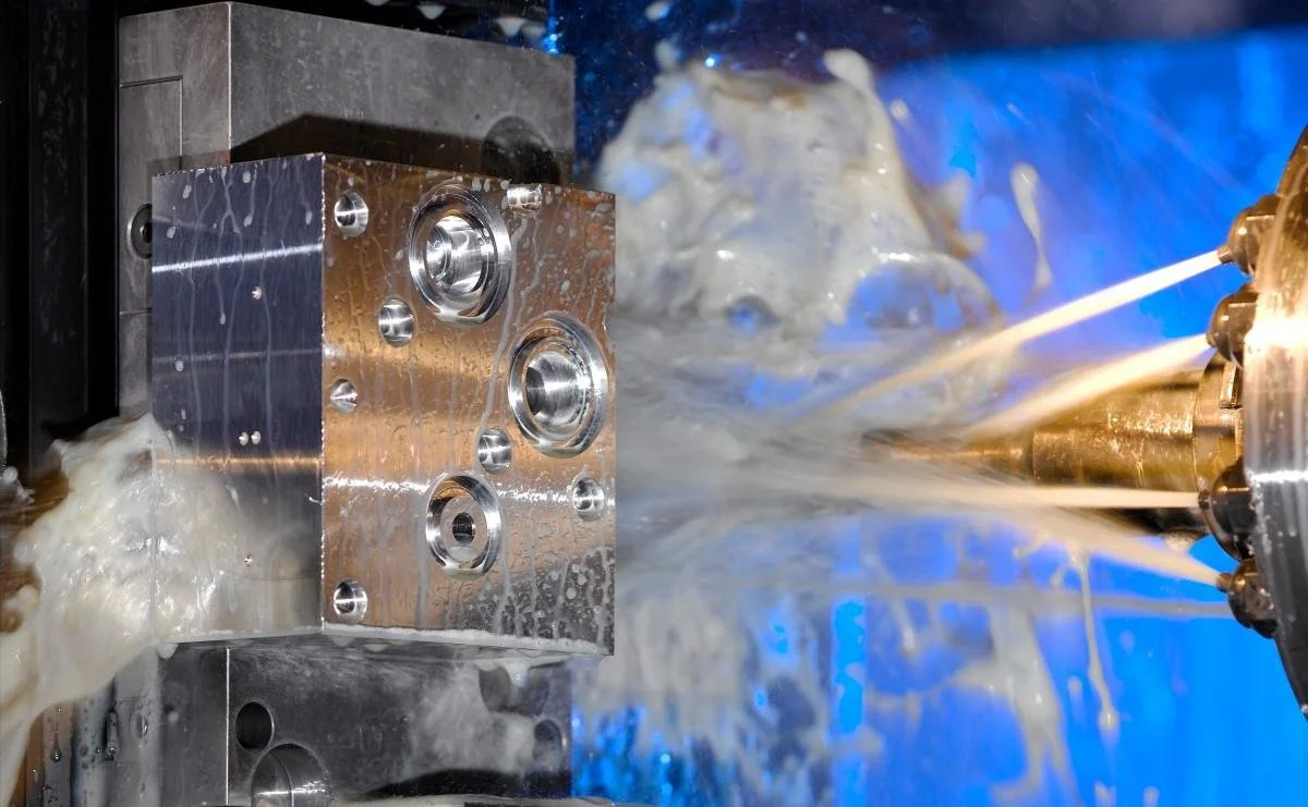 A nozzle spraying coolant onto a part for CNC machining