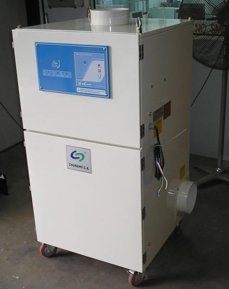 Portable dust collector positioned beside a production workstation