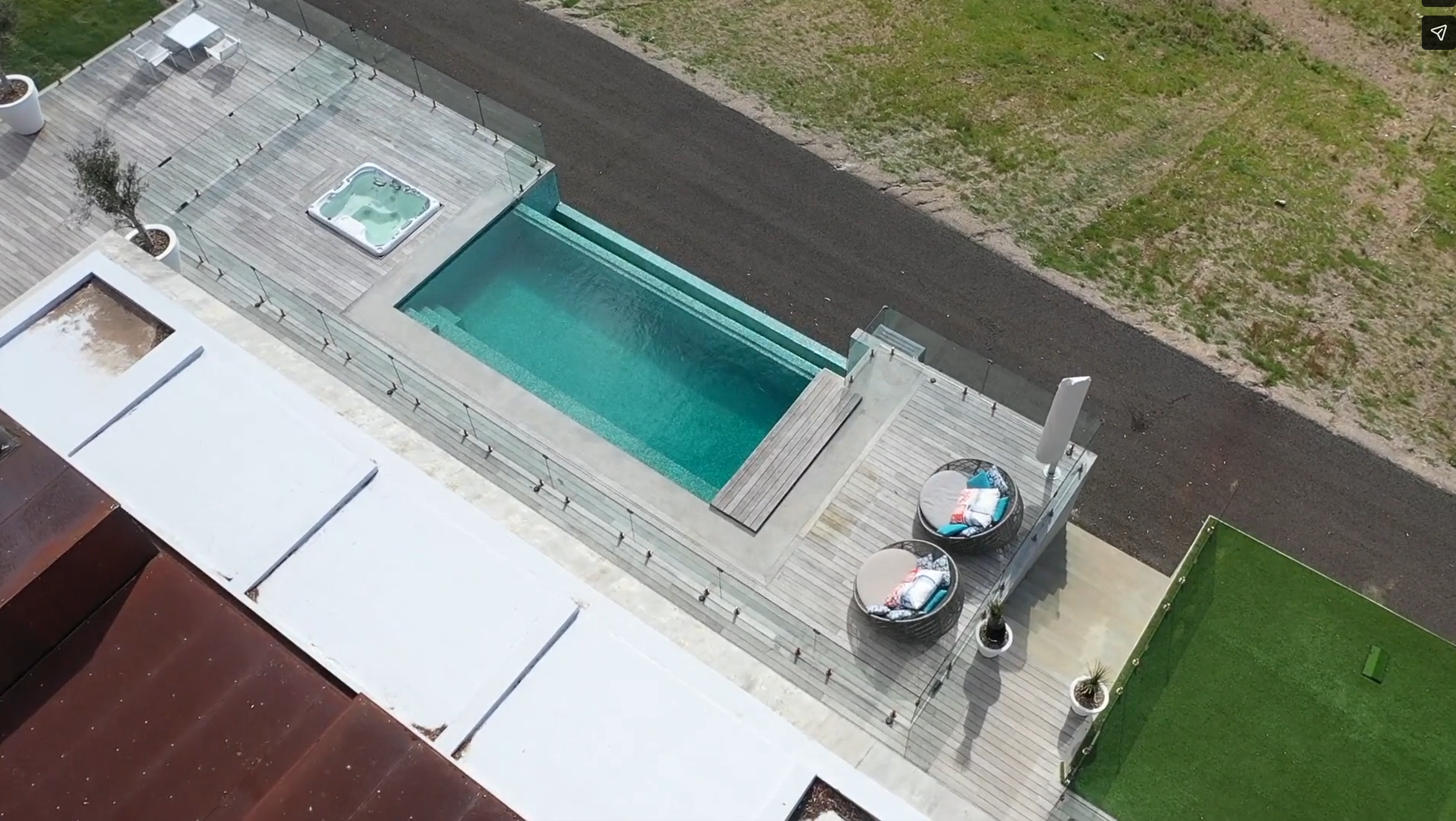 Frameless glass pool fence with stainless steel spigots on a timber deck