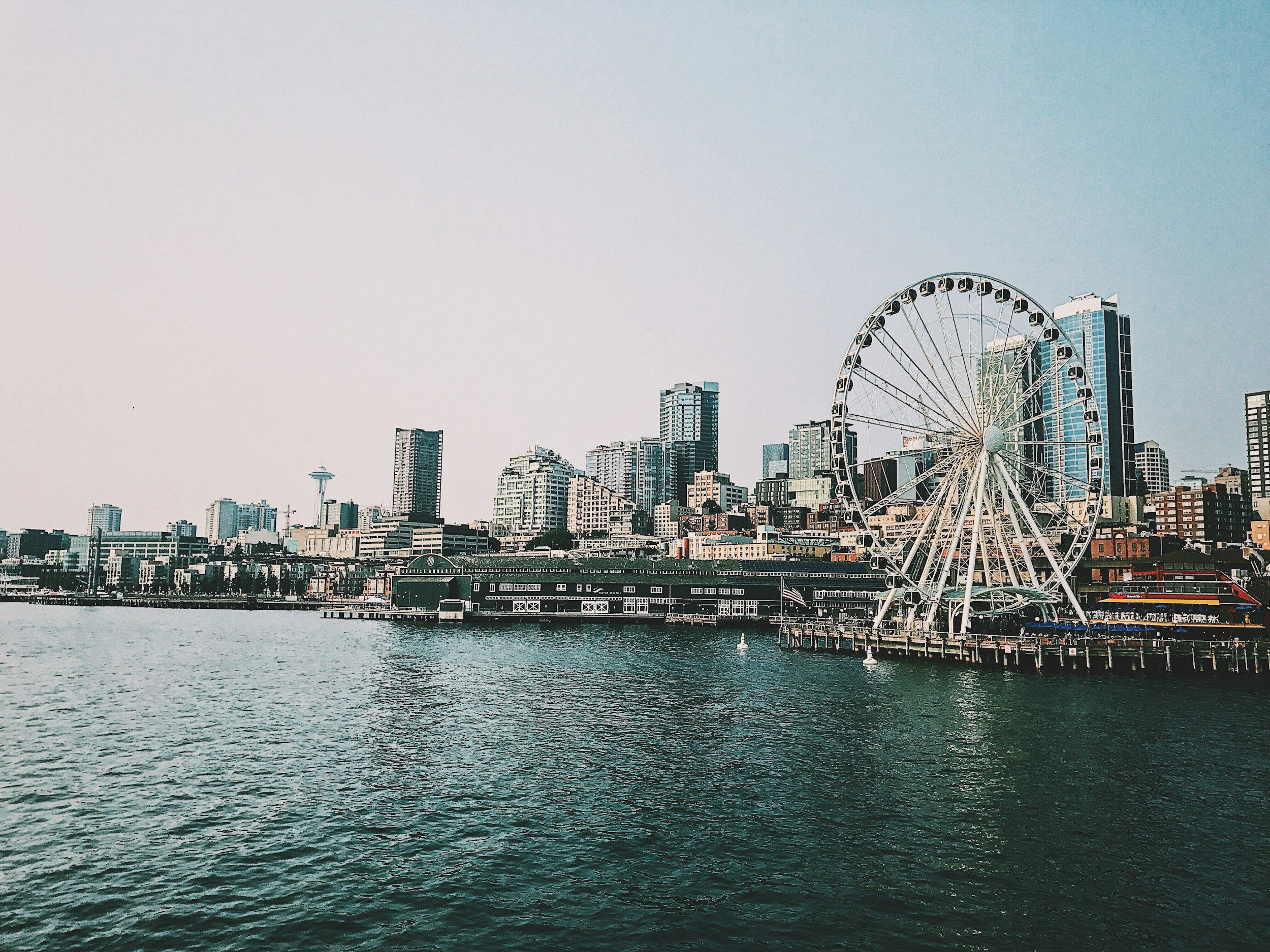 Seattle skyline with a large Ferris wheel by the waterfront during daytime.