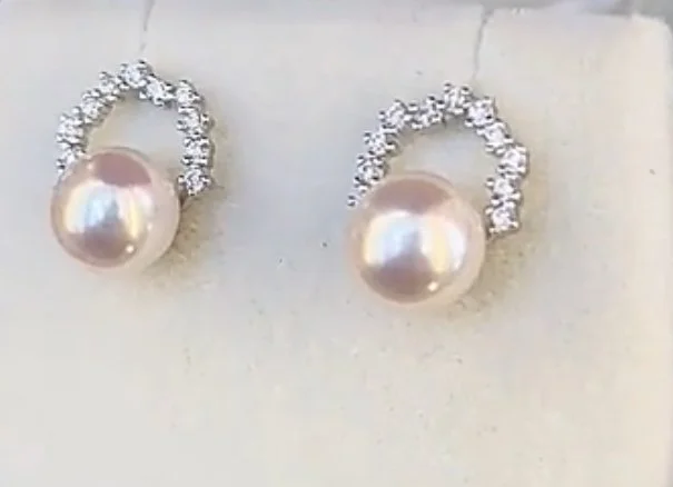 Pair of pearl stud earrings with a silver loop decorated with small rhinestones.