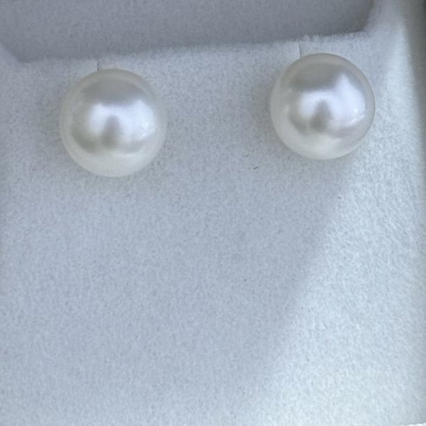 A pair of pearl earrings on a light-colored surface.