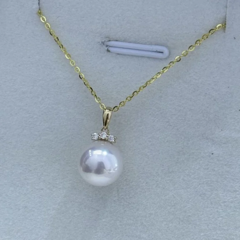 Silver chain necklace with a pearl pendant and small rhinestones above the pearl.