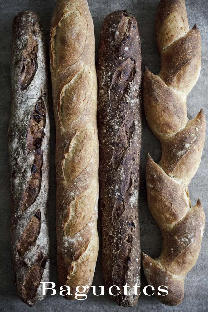 Four baguettes of French bread and several croissants on a baking sheet.