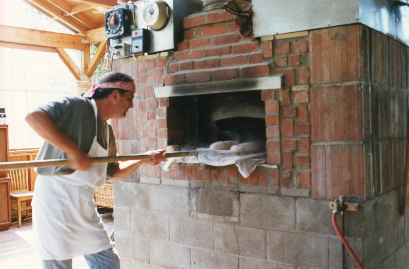 Ed Weber loading bread into the original wood burning oven using a long wooden peel.
