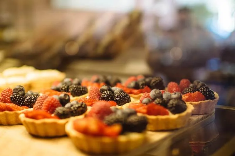 Close-up of mixed berry tartlets with strawberries, blackberries, blueberries, and raspberries on a display tray.