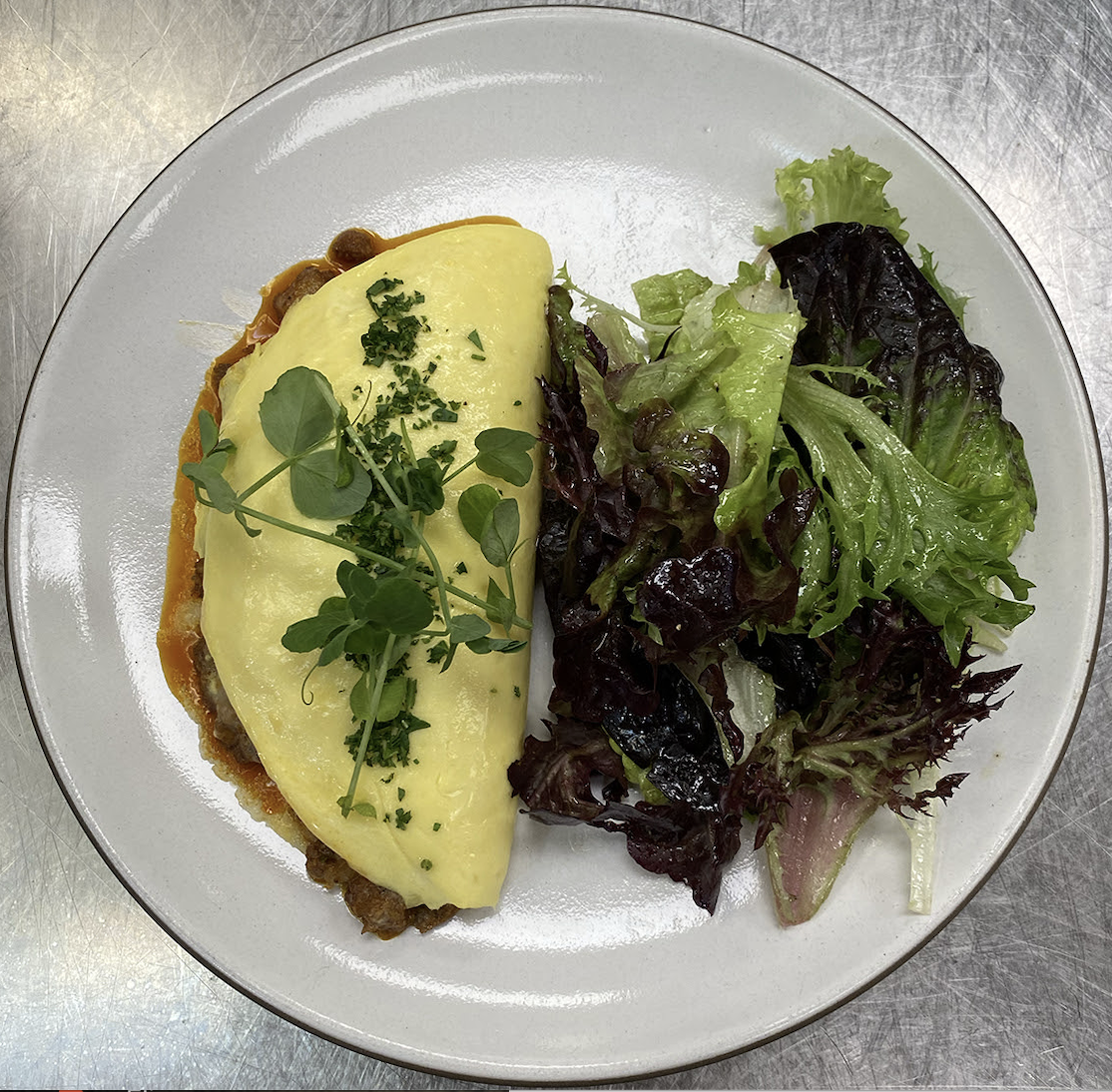 Omelette with herbs and salad greens on a white plate