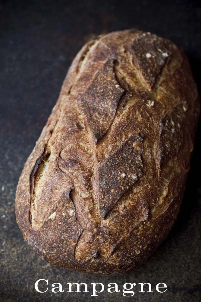 A rustic loaf of French bread with a dark crust and scoring on top, labeled "Champagne."