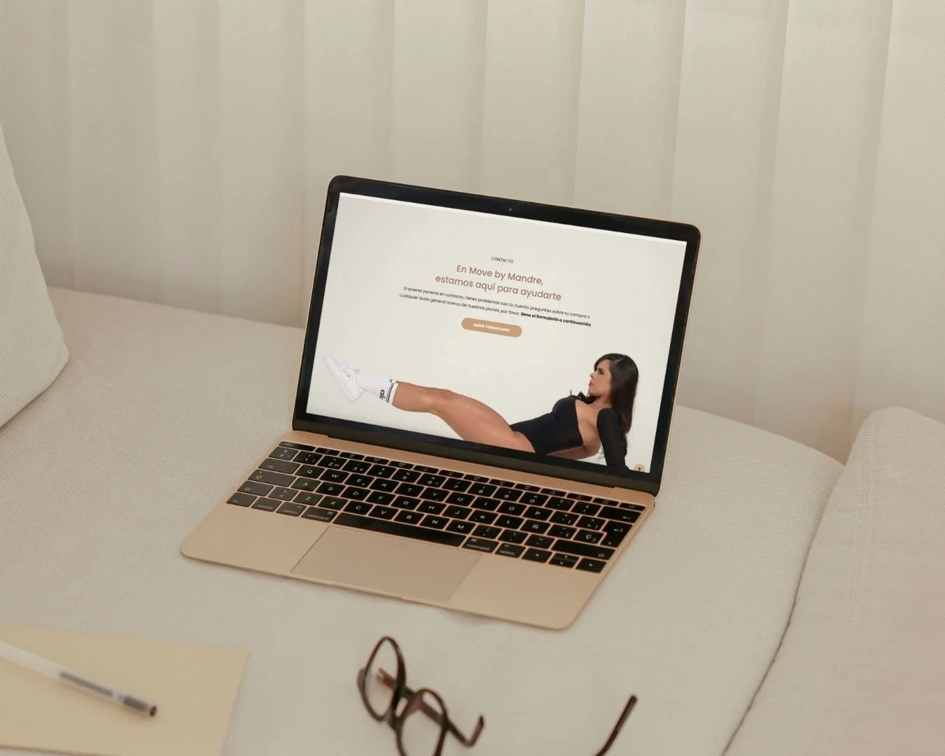 Pantalla de una laptop con un sitio web de una mujer en posición reclinada mostrando las piernas, en un entorno con fondo de cortinas blancas.