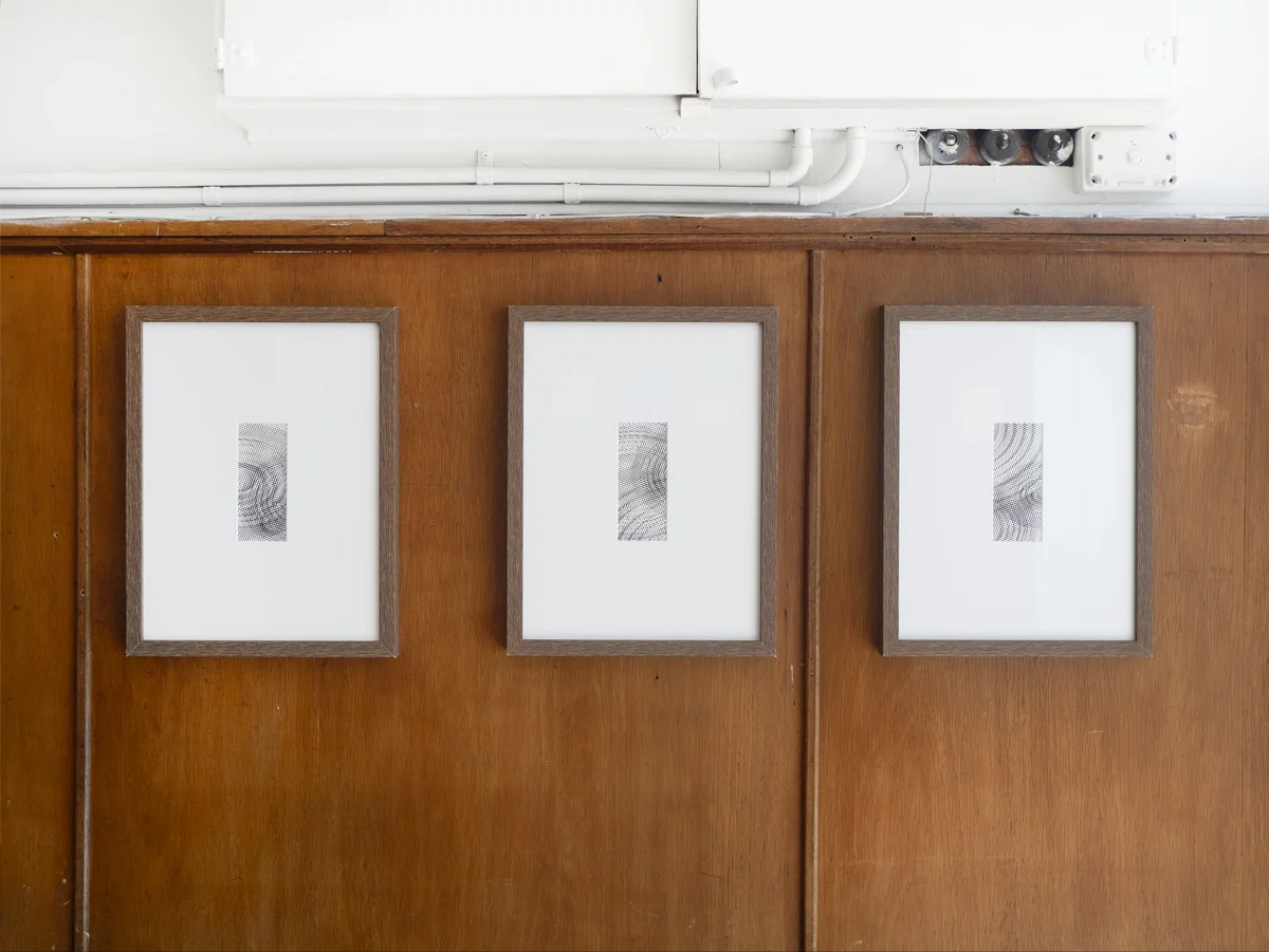 Three framed black-and-white abstract artworks by artist Thomas Pendergast hanging on a wooden wall.