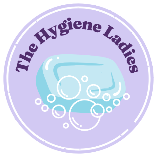 A logo with a purple and light blue color scheme featuring a bar of soap with bubbles and the text "The Hygiene Ladies" around the top in purple, circular design.